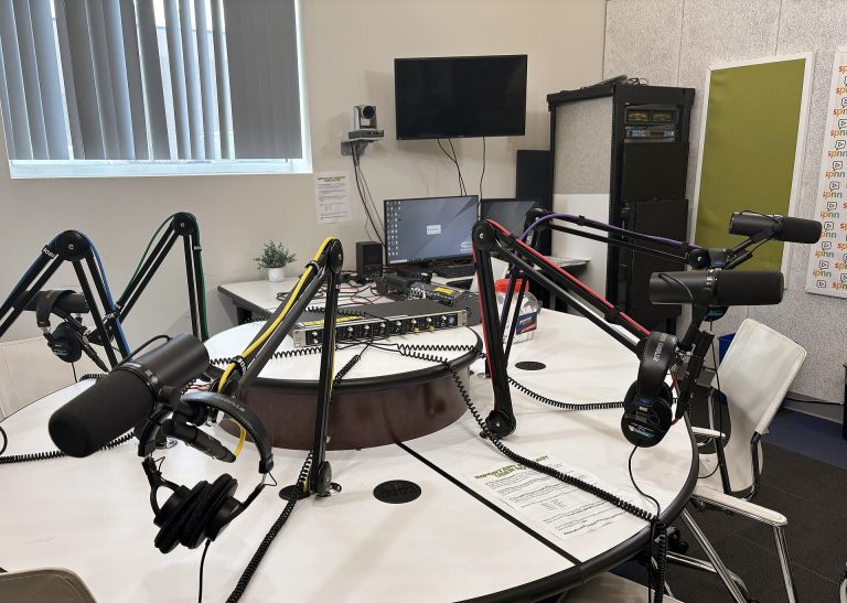 Professional microphones on boom arms set up in a podcast recording studio.